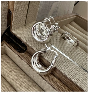 Close-up of polished S925 sterling silver hoop earrings in a vintage wooden jewelry box