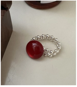 Macro shot of S925 silver beaded ring with a large translucent red stone on a white surface