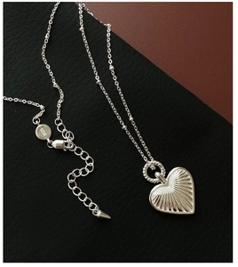 Close-up of S925 sterling silver heart necklace with radial texture on leather surface