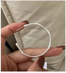Close-up of matte silver large hoop earrings showing the brushed texture and needle detail