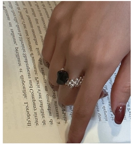 Detail of beaded S925 silver ring with a polished black gemstone on book background