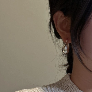 Minimalist S925 sterling silver drop-shaped hoop earring worn by a model in soft light