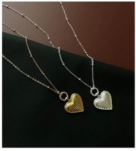 Detail of heart pendant necklaces with radial texture and beaded chain in gold and silver
