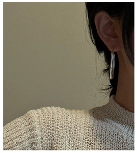 Detail view of large matte S925 silver hoop earrings with an irregular fluid design