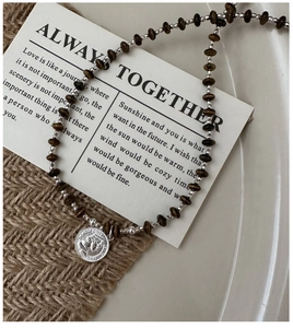 Detail of vintage beaded necklace with tiger eye stones and silver coin pendant
