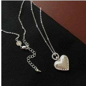 Macro view of S925 sterling silver heart necklace showing radial texture and hallmarks