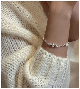 Detail of S925 sterling silver layered bead bracelet worn on a cozy knit sweater sleeve