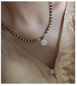 Macro detail of S925 silver coin pendant on vintage brown beaded necklace for women