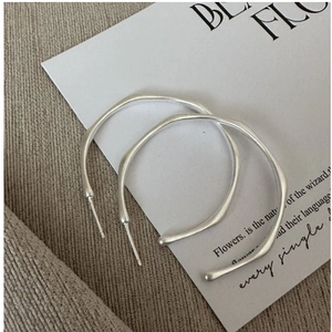 Close-up of S925 sterling silver hoop earrings with irregular wavy design and matte finish