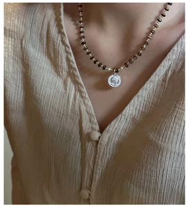 Detail of tiger eye stone and pearl necklace with a vintage silver coin pendant