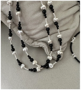 Detail of S925 silver necklace with black agate beads and irregular metallic textures