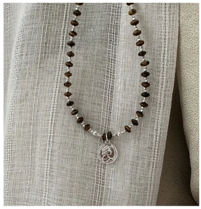 Detailed view of vintage S925 silver coin pendant on brown beaded chain necklace