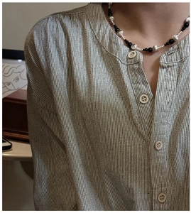 Detail of S925 silver necklace with black agate and cat eye beads on striped shirt