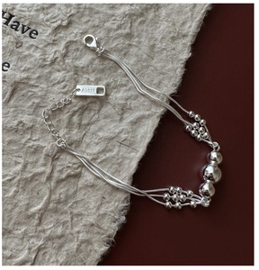 Macro detail of S925 sterling silver triple-layer beaded bracelet with mirror finish