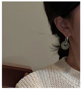 Close-up of S925 silver hoop earrings with green jade pendant worn by a model