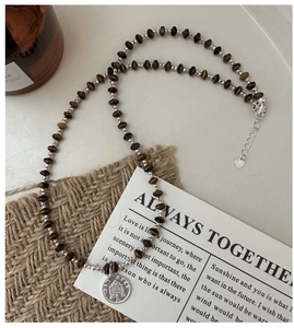 Macro detail of S925 silver coin pendant and brown faceted beads on retro necklace