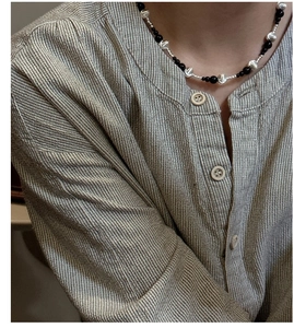 Macro shot of minimalist S925 silver necklace with black agate beads on striped linen fabric