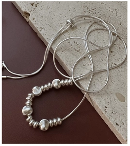 Macro detail of S925 silver snake chain with textured metal beads on a stone surface