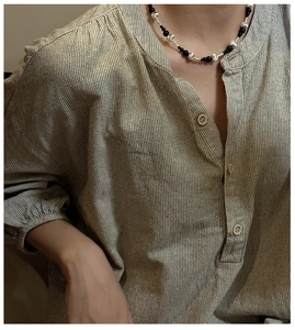 Close-up of a striped cotton-linen shirt with wood buttons and beaded necklace detail