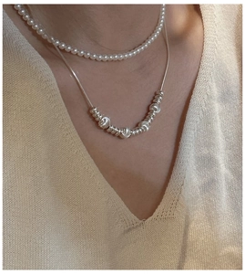 Close-up of S925 silver layered necklace with snake chain and round pearls on a model