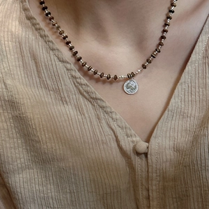 S925 sterling silver coin pendant necklace with brown beads on a woman wearing a shirt