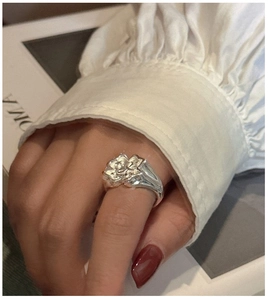 Détail macro d'une bague fleur argentée aux pétales polis portée au doigt