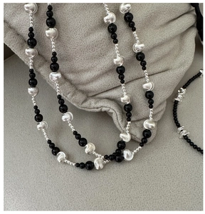 Close-up of S925 silver necklace with black agate beads and brushed metal texture