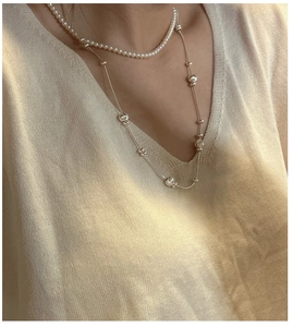 Close-up of a layered S925 silver necklace set with white pearls and bead details