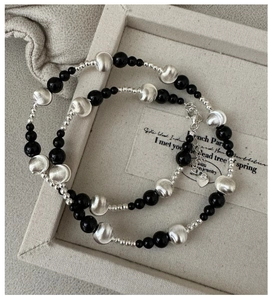 Detail of S925 silver necklace with black agate beads and brushed metal texture