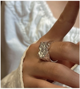 Gros plan d'une bague en argent S925 avec bords ondulés et gravure florale vintage