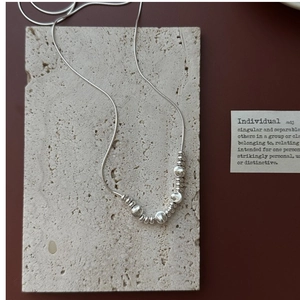 Detailed close-up of S925 silver snake chain necklace with textured metallic beads