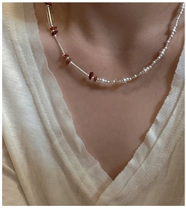 Detail of S925 silver beaded necklace with red crystal stones on a white knit sweater