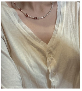 Detail shot of a beaded silver necklace with garnet stones on a knit cardigan