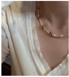 Detail of S925 sterling silver beaded necklace with red-brown stones on a model