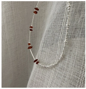 Macro detail of S925 sterling silver beaded necklace with red garnet gemstones on linen