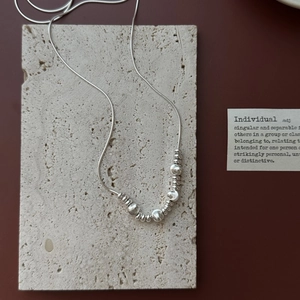 S925 sterling silver snake chain necklace with silver beads on a textured stone plate