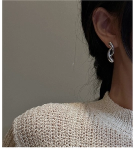 Close-up of model wearing silver S925 curved cross earrings with a minimalist design