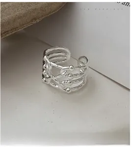 Macro detail of silver S925 multi-layered criss-cross open ring with metallic bead accents