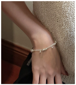 Detail of minimalist S925 sterling silver chain bracelet with rings on a model's wrist