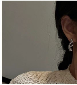 Detail of S925 sterling silver curved double loop earrings worn on a model's ear