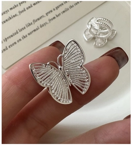 Macro shot of silver butterfly ring with intricate woven texture on index finger