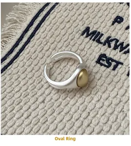 Detail of matte S925 sterling silver ring featuring a golden oval bead and brushed finish