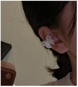 Macro view of butterfly ear cuff with hollow woven silver wing texture and minimalist design