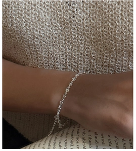 Detailed view of S925 sterling silver heart chain bracelet on a wrist with a soft sweater