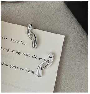 Macro shot of liquid-style S925 sterling silver curved earrings with polished finish
