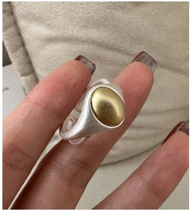 Detail of matte two-tone S925 silver ring with golden oval bead on a model's finger