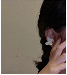 Detail of silver butterfly ear cuff with hollow design on female model's ear