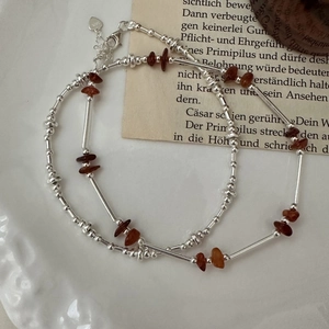 Minimalist S925 silver beaded bracelet with reddish garnet stones on a vintage plate