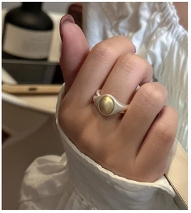 Macro detail of a vintage wide-band mixed metal ring with matte gold oval centerpiece
