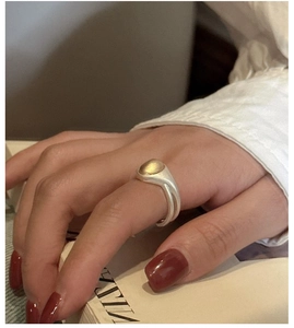 Detail view of a minimalist S925 silver ring featuring a matte gold bean on the hand